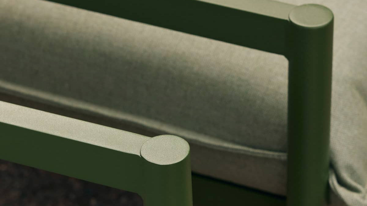 Closeup of aluminum armrests from a portion of a stylish green outdoor sofa