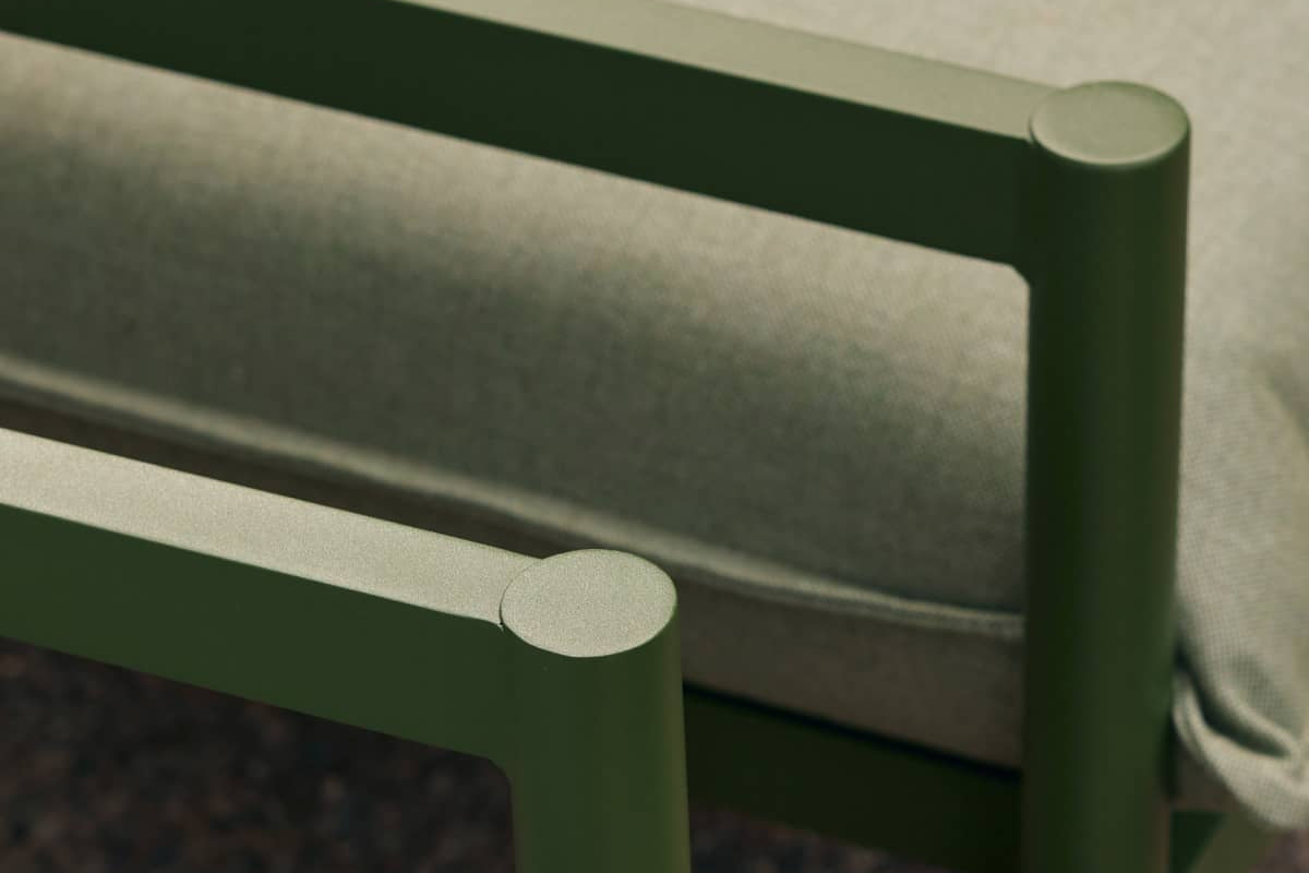 Closeup of aluminum armrests from a portion of a stylish green outdoor sofa