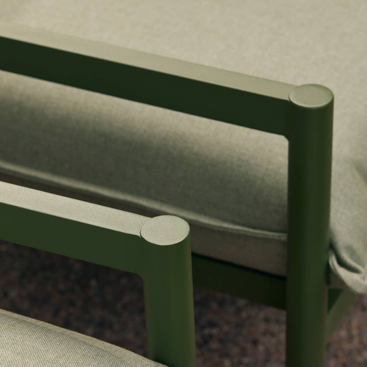 Closeup of aluminum armrests from a portion of a stylish green outdoor sofa