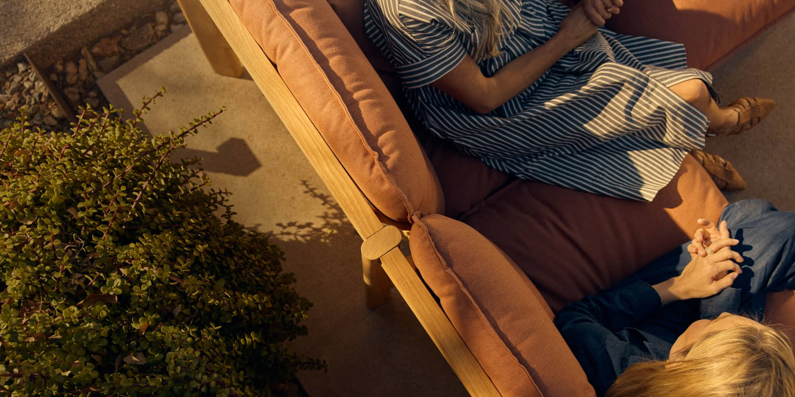 Overhead image of two women sitting and relaxing on an outdoor sectional