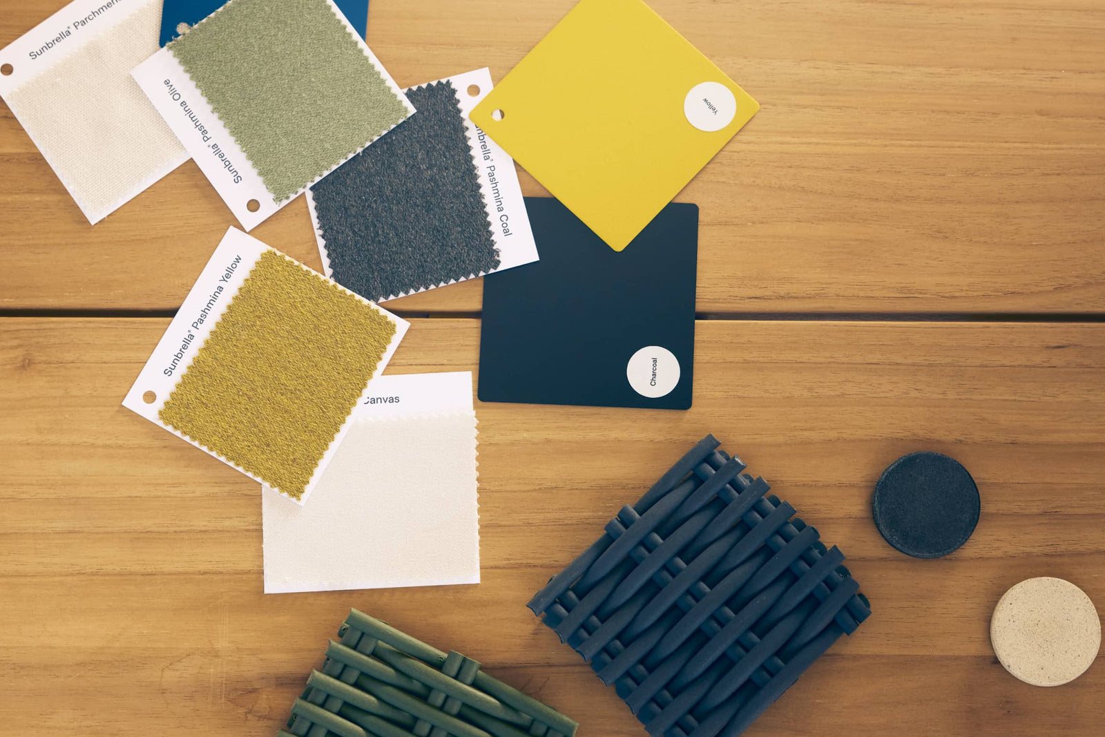 Fabric, wicker, and concrete swatches scattered across a wooden table top
