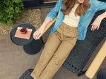 Multiple angles of two woman sitting on chairs on a patio constructed with flexible woven strap.