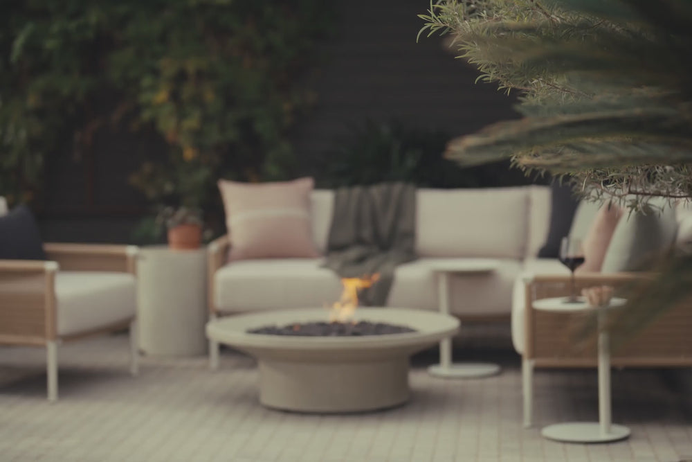 Video of light grey fire table with lava rock and flame burning. 