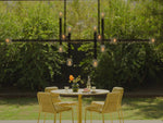 Video of a yellow dining table with four matching chairs and seat pads. Specific focus on the Neighbor XY Dining Chair, a yellow, metal dining chair with a Sunbrella, yellow seat pad.