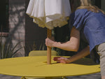 Video of a yellow dining table with four matching chairs and seat pads. Specific focus on the Neighbor XY Dining Table, a yellow, metal dining table with integrated umbrella holder.