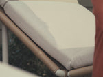 Video of synthetic rattan chaise lounge outdoor chair with off-white cushions.